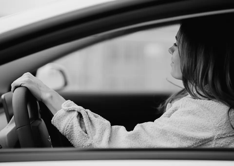 A woman driving, seen through the car window